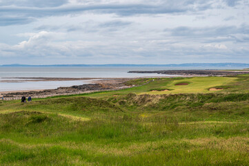 View of a fairway on a links golf course, overlooking the sea, in Wales. Bunkers can be seen, with...