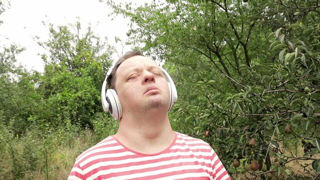 Man with down syndrome listening to music in the garden. Peaceful atmosphere. Free mind