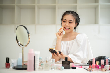 A beautiful Asian woman applies cushion or press powder on her face. Lifestyle concept