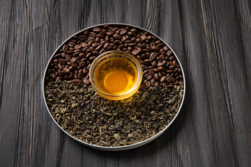 Composition of green tea, coffee beans and tea in a cup on a dark background.