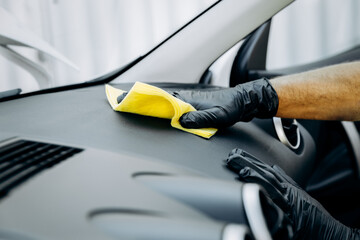 A man dusts the inside of a car with microfiber cloth. Worker cleaning car.  Car washes, cleaning, car service concept.