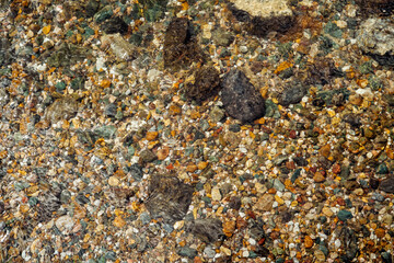 Pebbles at the bottom of a clear river. Colorful stone underwater pattern. Abstract natural background, mock up for design, copy space.