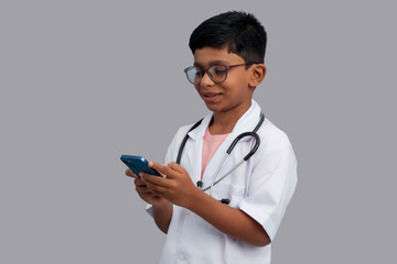 Indian Asian kid boy aged 7 to 8, wearing a doctor apron with stethoscope. standing and watching...