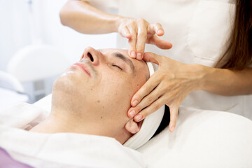 Obraz na płótnie Canvas close-up of a beautician's hands performing a facial massage on a man, skin care concept