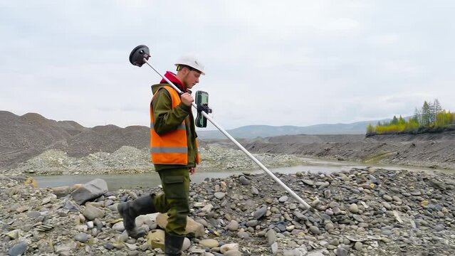 Surveyor Specialist Measures Gold Mine Area By Theodolite Equipment. Young Surveyor With Prism Pole Equipment Measuring Elevation Of Gold Mine Ground. Two Male Surveyors Working At Gold Mining Site