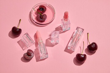 Against the pink background, cute lipsticks with transparent outer shell decorated with fresh...