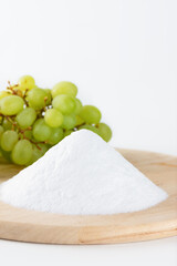 Bunch of white sugar with fresh grape on a wooden board on a light background, grape sugar, selective focus.