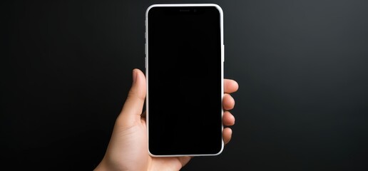 BLANK SCREEN SMARTPHONE MOCKUP, Mock-up, Template, Sample, Black background, Hand. Young male hand holding a smartphone model in vertical position. Close-up and focus on it and frontal view.