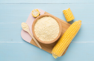 Corn flour with fresh cobs on wooden background, top view