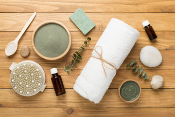 Composition with cosmetic clay and spa products on wooden background, top view