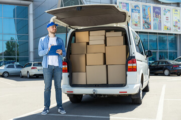 A courier with a folder in his hands near a car with boxes