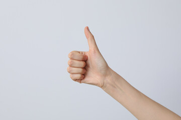 Female hand showing thumb up on light background