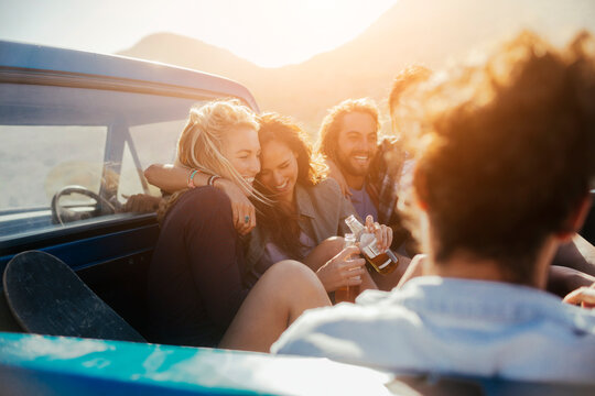 Diverse and mixed group of young people on a road trip while sitting in the back of a truck bed