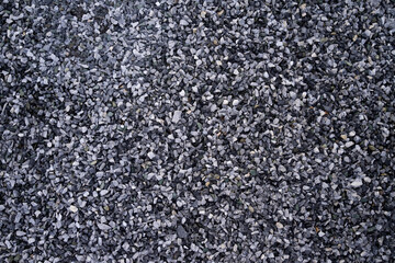 Small pebble stone background, dark wet gravel and gray dry gravel. Black small road