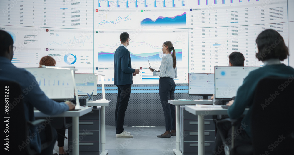 Leinwandbilder zoom out back view shot of male and female analysts discussing financial data on big digital screen 