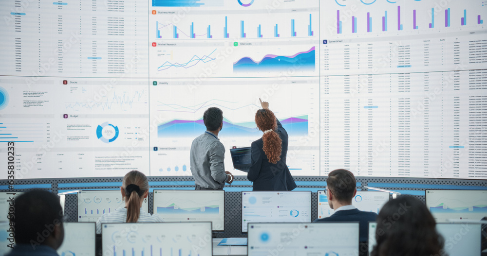 Poster Wide Zoom In Back Shot Of Diverse Male And Female Risk Managers Analyzing Data On Digital Screen In Monitoring Room. Multiethnic Employees Working On Computers For Succesful Venture Capital Company