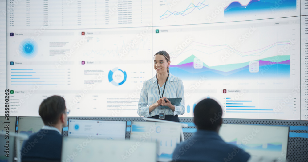 Aufkleber Caucasian Female Project Manager With Tablet Computer Is Giving Presentation To Diverse Employees In Front of Big Digital Screen In Monitoring Room. Team Of Data Scientists Listening To New Objectives