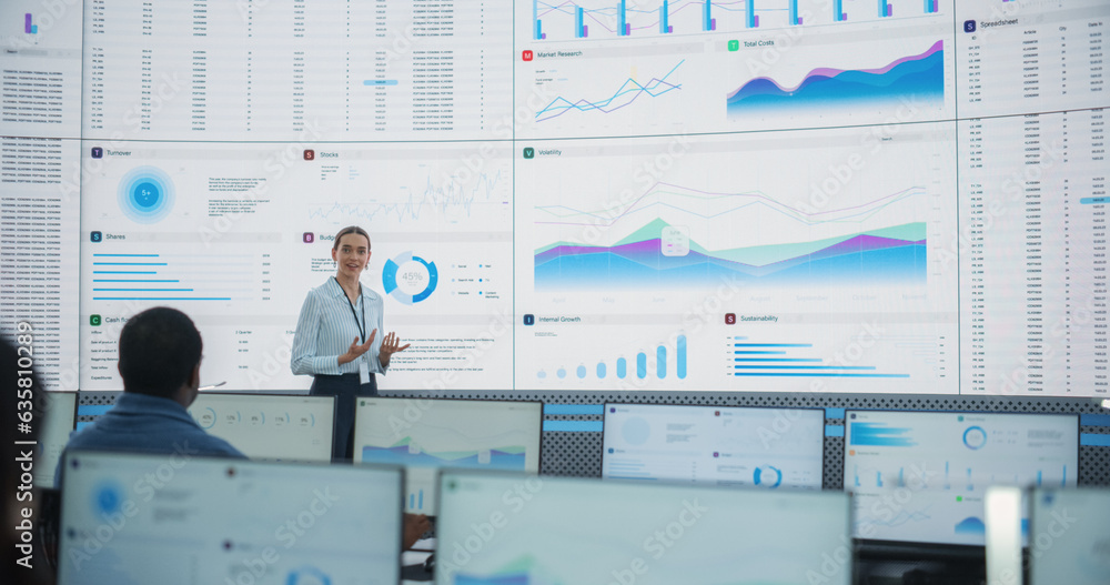 Fototapete Caucasian Female Data Scientist With Tablet Computer Is Reviewing Reports Of Diverse Employees on Big Digital Screen In Monitoring Room. Team Of Analysts Listening To New Objectives And Tasks.