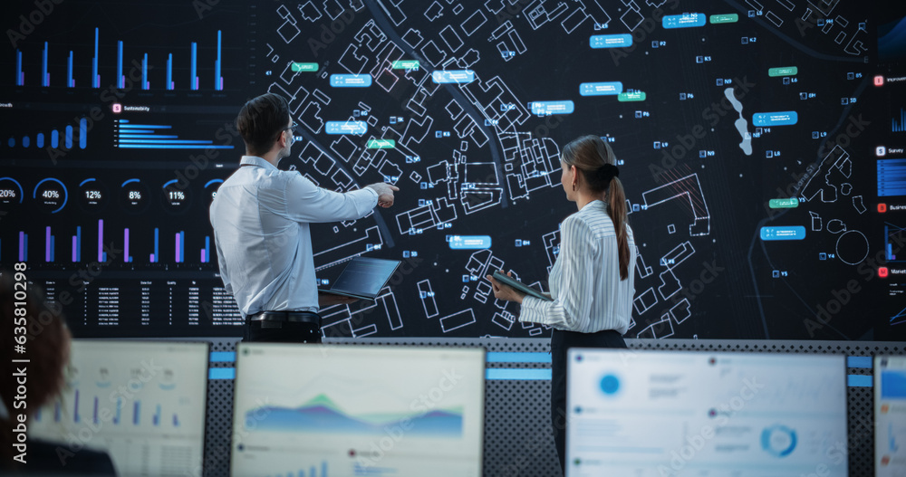 Leinwandbilder male and female logistics specialists discussing new routs of delivery in front of big digital scree