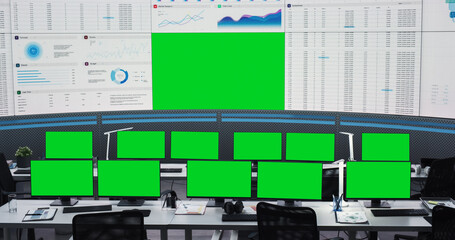 Obraz premium Empty Modern Monitoring Office With Green Screen Chromakey On Big Digital Screen And Desktop Computer Monitors Of Employees. Mockup Template Of Successful AI Or Deep Learning Company Workspace.