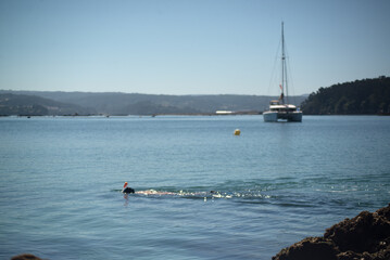 The catamaran stands in the sea bay and the diver floats on the water