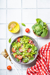 Green vegetable salad with fresh leaves. Top view on white tile background.