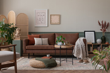 Creative composition of warm and cozy living room interior with mock up poster frame, brown sofa,...