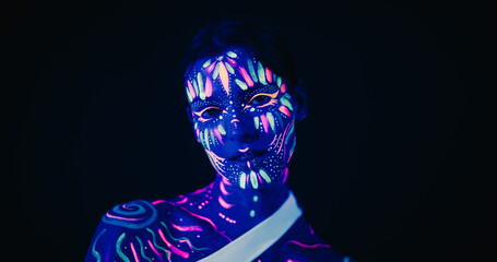 Young Sensual Model Poses with Grace and Poise, Her Vivid Body Paint Complementing Dark Abstract...