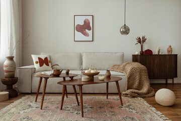 Domestic and cozy interior of living room with mock up poster frame, modern beige sofa, oval wooden...