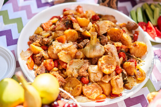 Dimlama - stewed vegetables with the meat in a large Central Asian cauldron. Uzbek cuisine. Fried vegetables with meat. Outdoor lunch, picnic