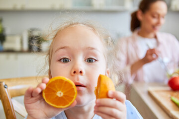 Girl playing with orange slices at home