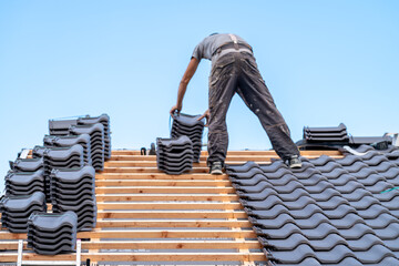 a craftsman installs a fired ceramic tile on the roof of family house
