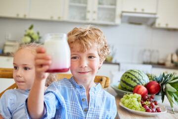 Smiling brother holding parfait jar with sister