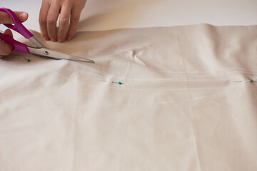 Fototapeta premium Dressmaker cuts dress detail on the sketch lines. Workplace of seamstress.