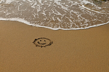 Sand on the beach, sea foam, drawing on the sand.