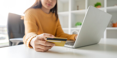 Closeup asian woman holding credit card and smartphone, sitting at home, happy satisfied young female customer shopping online