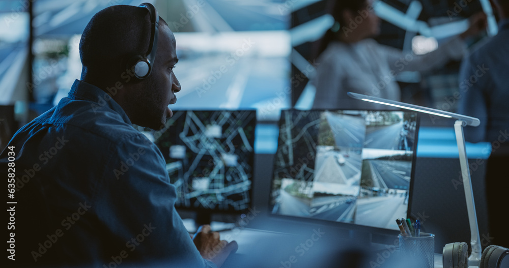 Poster African Specialist in a Dark High-Tech Monitoring Room, Concentrated on a Call and Computer Work. Black Technical Support Manager Using Headphones with Built-In Mic for Communication with Client