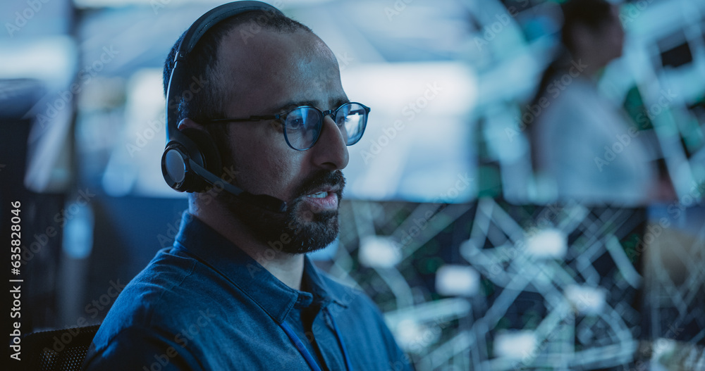Poster portrait of a surveillance officer wearing a headset, working in a central office hub for cybersecur