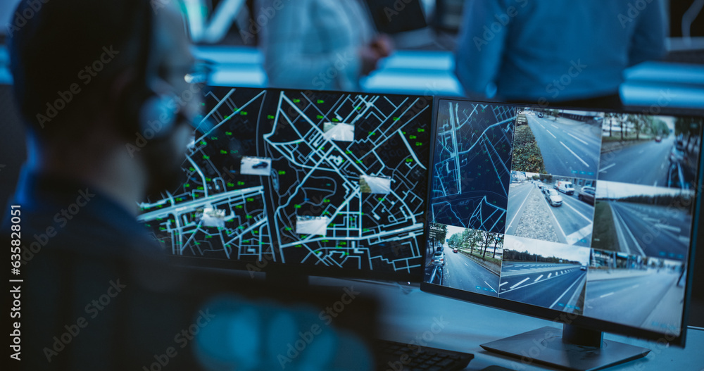 Poster Multiethnic Specialist in a Dark High-Tech Monitoring Room, Concentrated on a Call and Computer Work. Technical Support Manager Using Headphones with Built-In Mic for Communication with Customers