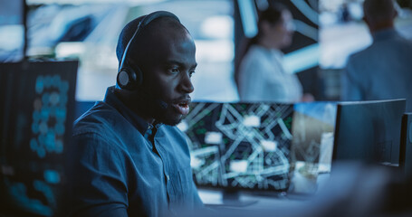 Handsome Surveillance Specialist in a Modern Monitoring Room with Displays and Computers. Black Man...