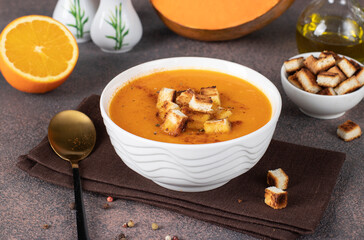 Pumpkin puree soup with orange, served in a white bowl with croutons