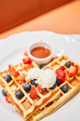 Classic Viennese waffles with ice cream, berries and Maple syrup. Breakfast in cafe. Table in the restaurant.