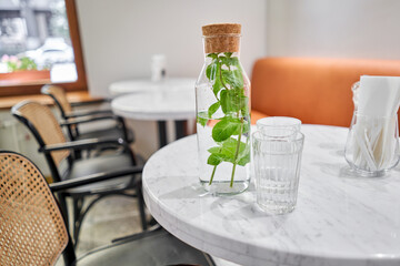 A refreshing drink on a hot summer day. A table in a cafe. A decanter and two glasses. Healthy drinks, diet, detox with fruit water in glass bottle with mint