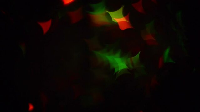 Christmas Quadrangular Bokeh Stars. Festive Twinkling moving background. Green and red defocused bokeh stars on a black transition or overlay.
