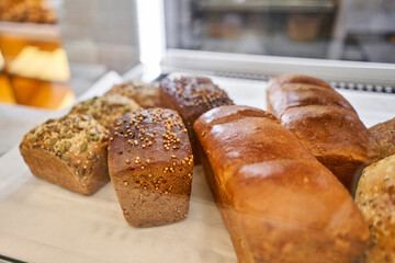 Different kinds of bread on the counter in the bakery shop. Fresh bread counter. Modern bakery with different kinds of bread, cakes and buns 