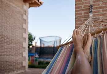 Unrecognizable person relaxing in a hammock. Point of view shot of the legs of an anonymous young...