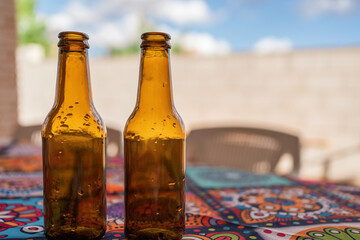 Empty brown bottles of beer on terrace table with tablecloth.