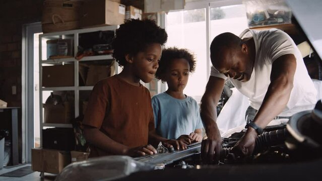 African Father Teaches Sons to Fix Vehicle in the Garage