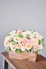 Florist woman creates flower arrangement in a wooden box. Beautiful bouquet of mixed flowers. Floral shop concept . Handsome fresh bunch. Flowers delivery