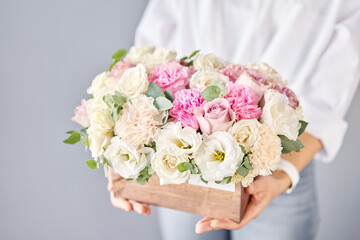 Florist woman creates flower arrangement in a wooden box. Beautiful bouquet of mixed flowers. Floral shop concept . Handsome fresh bunch. Flowers delivery